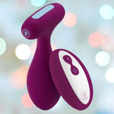 The Femme Funn PLUA Vibrating Remote Control Butt Plug in fuchsia is set against a soft, blurred background with various pastel-colored lights. The remote features simple white accents and buttons for easy operation, ensuring the waterproof design is both user-friendly and versatile.
